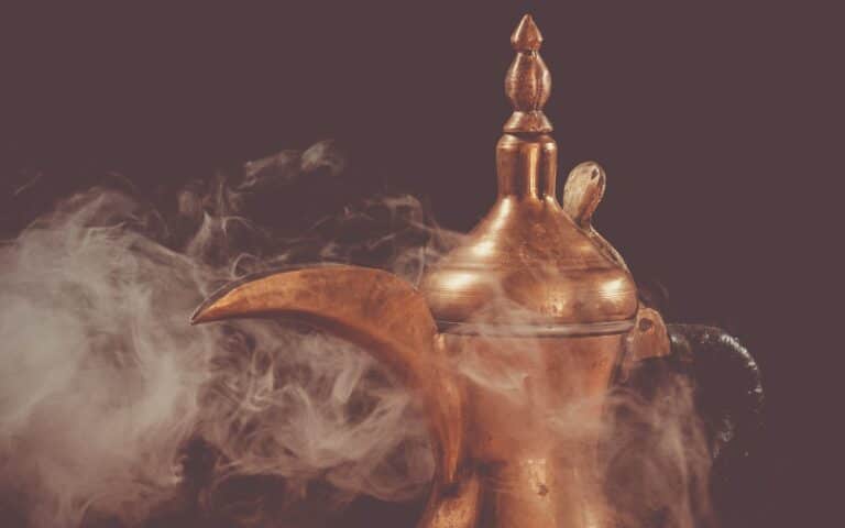 brass teapot with smoke on black background